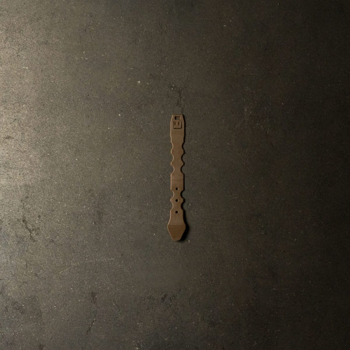 A tan Malice Clip designed for securely attaching MOLLE-compatible pouches and accessories to tactical vests, plate carriers, and backpacks.