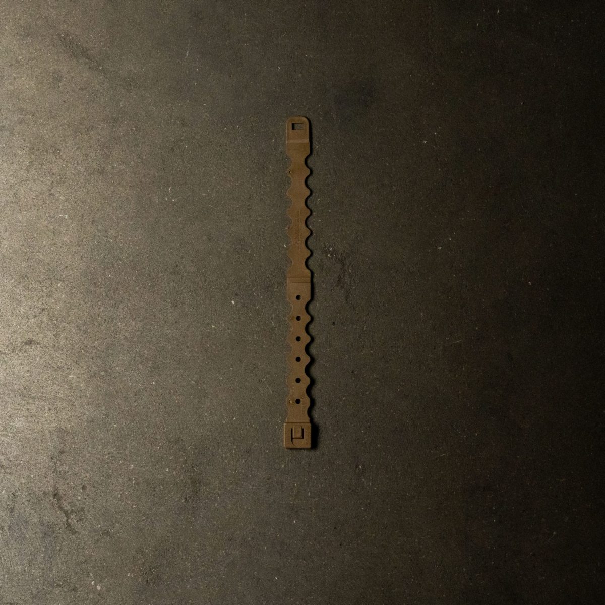 A tan Malice Clip designed for securely attaching MOLLE-compatible pouches and accessories to tactical vests, plate carriers, and backpacks.